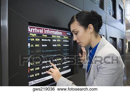 Side profile of a businesswoman looking at an arrival departure board in an airport View Large Photo Image Stock Photograph - Side profile of a businesswoman looking at an arrival departure board in an airport. Fotosearch