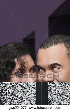 Stock Photo - Close-up of a young couple hiding their face with a textbook. Fotosearch