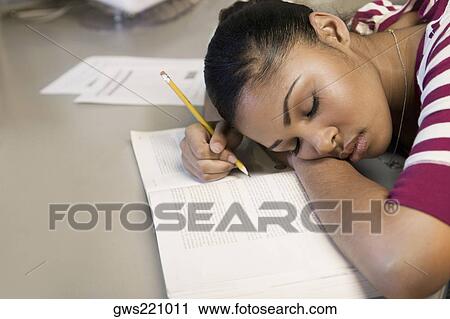Stock Image - Close-up of a young man napping on a book. Fotosearch