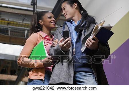 Low angle view of a young couple holding their textbooks View Large Photo Image Stock Image - Low angle view of a young couple holding their textbooks. Fotosearch