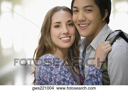 Picture - Portrait of a young couple embracing each other and smiling. Fotosearch