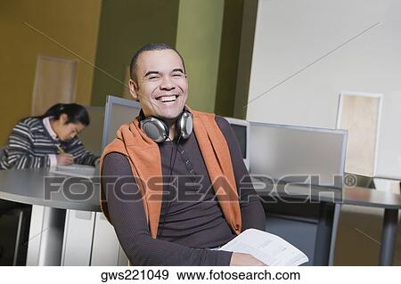 Portrait of a young man sitting in a computer lab and laughing View Large Photo Image Stock Photo - Portrait of a young man sitting in a computer lab and laughing. Fotosearch