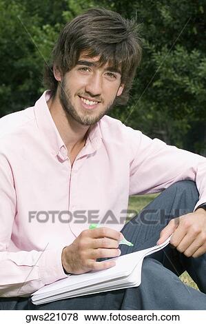 Portrait of a young man writing with a pen on a notepad View Large Photo Image Stock Photo - Portrait of a young man writing with a pen on a notepad. Fotosearch