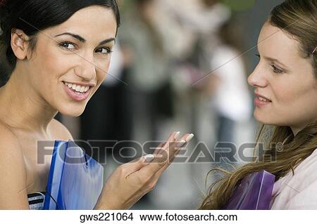 Picture - Portrait of a young woman talking to her friend and smiling. Fotosearch