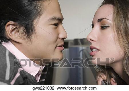 Stock Image - Side profile of a young couple romancing. Fotosearch