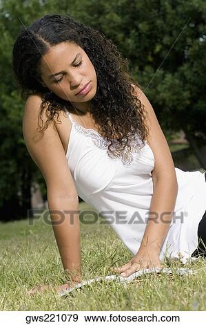 Teenage girl sitting in a lawn and reading a book View Large Photo Image Stock Photo - Teenage girl sitting in a lawn and reading a book. Fotosearch