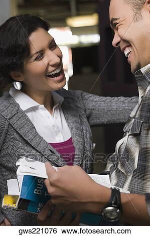Stock Photograph - Two university students talking and smiling in a corridor. Fotosearch