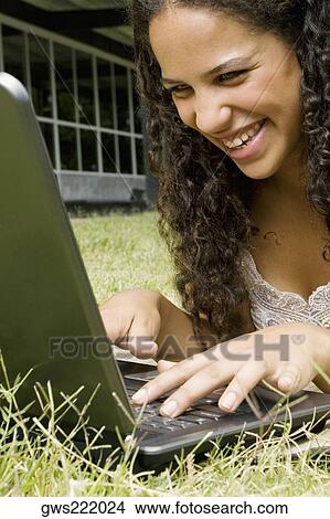 Picture - Close-up of a teenage girl working on a laptop and smiling. Fotosearch