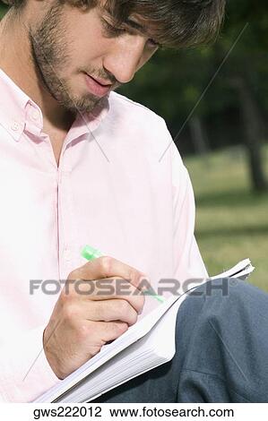 Close-up of a young man writing with a pen in a notepad View Large Photo Image Stock Image - Close-up of a young man writing with a pen in a notepad. Fotosearch