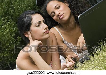 Female university students working on a laptop in a lawn View Large Photo Image Stock Image - Female university students working on a laptop in a lawn. Fotosearch