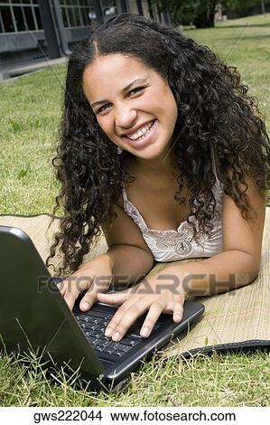 Picture - Portrait of a teenage girl working on a laptop and smiling. Fotosearch