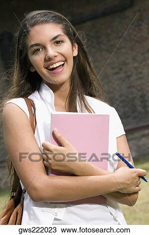 Stock Image - Portrait of a young woman holding a book and smiling. Fotosearch