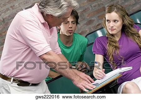 Professor assisting his students in a classroom View Large Photo Image Stock Photograph - Professor assisting his students in a classroom. Fotosearch