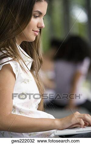Side profile of a young woman using a laptop View Large Photo Image Stock Image - Side profile of a young woman using a laptop. Fotosearch