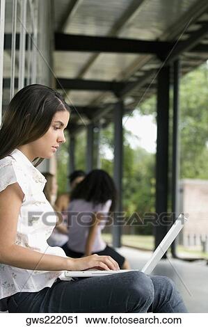 Stock Image - Side profile of a young woman working on a laptop. Fotosearch