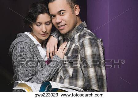 Stock Photo - Close-up of a young couple leaning against a wall. Fotosearch