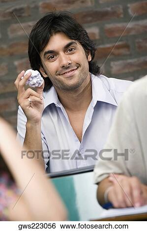 Portrait of a young man holding a crumpled paper in a classroom View Large Photo Image Stock Photograph - Portrait of a young man holding a crumpled paper in a classroom. Fotosearch
