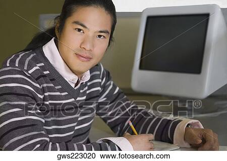 Portrait of a young man sitting in a computer lab and studying View Large Photo Image Stock Image - Portrait of a young man sitting in a computer lab and studying. Fotosearch