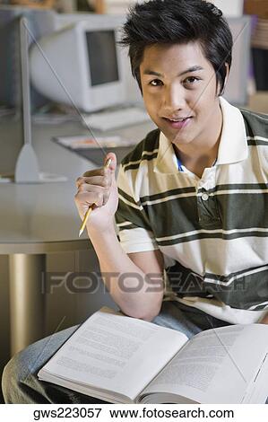 Portrait of a young man sitting in a computer lab and smiling View Large Photo Image Stock Photo - Portrait of a young man sitting in a computer lab and smiling. Fotosearch