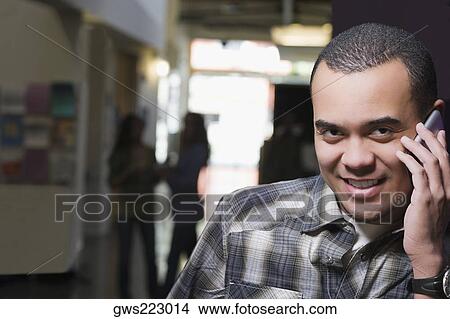 Portrait of a young man talking on a mobile phone and smiling View Large Photo Image Picture - Portrait of a young man talking on a mobile phone and smiling. Fotosearch