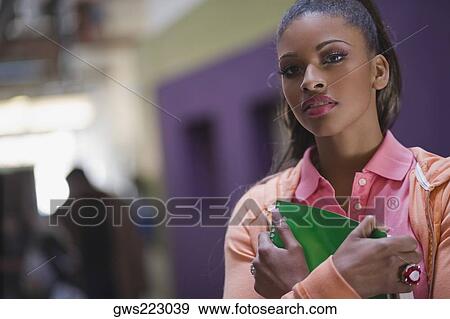 Portrait of a young woman holding a textbook View Large Photo Image Stock Photo - Portrait of a young woman holding a textbook. Fotosearch
