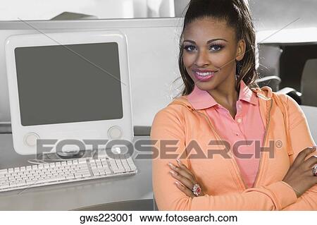 Portrait of a young woman sitting in a computer lab and smiling View Large Photo Image Stock Image - Portrait of a young woman sitting in a computer lab and smiling. Fotosearch