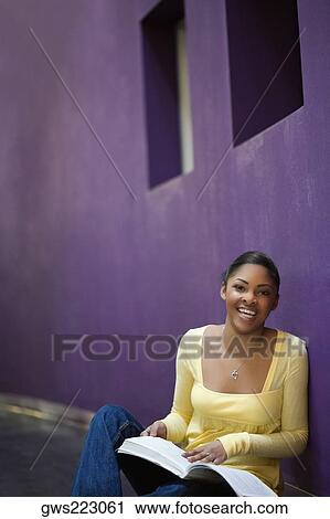 Stock Image - Portrait of a young woman sitting in a corridor and laughing. Fotosearch