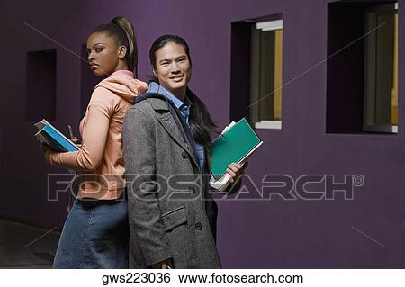 Young couple standing back to back in a corridor View Large Photo Image Stock Photograph - Young couple standing back to back in a corridor. Fotosearch