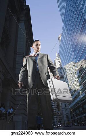 Stock Image - Low angle view of a businessman holding a briefcase. Fotosearch