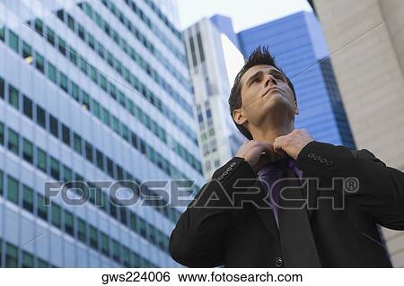 Low angle view of a businessman loosening his tie View Large Photo Image Stock Photograph - Low angle view of a businessman loosening his tie. Fotosearch