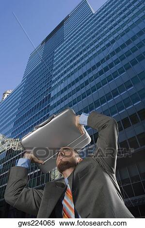 Low angle view of a businessman using his briefcase as a shade View Large Photo Image Stock Photography - Low angle view of a businessman using his briefcase as a shade. Fotosearch
