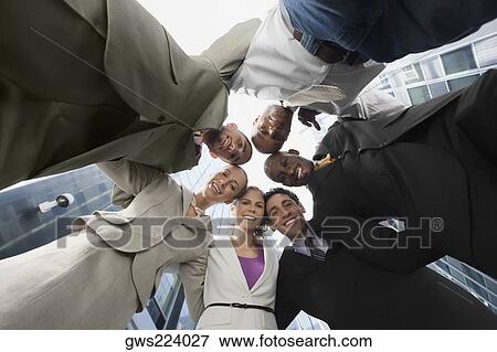Stock Photo - Low angle view of business executives standing in a huddle. Fotosearch