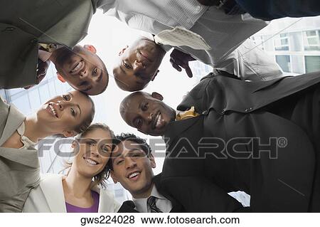 Stock Photo - Low angle view of business executives standing in a huddle. Fotosearch