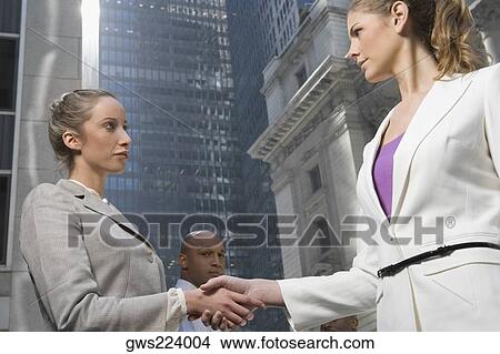 Low angle view of two businesswomen shaking hands View Large Photo Image Picture - Low angle view of two businesswomen shaking hands. Fotosearch