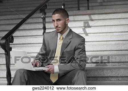 Portrait of a businessman sitting on a staircase and using a laptop View Large Photo Image Stock Image - Portrait of a businessman sitting on a staircase and using a laptop. Fotosearch