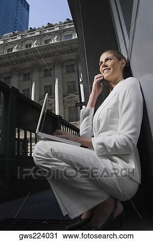 Side profile of a businesswoman talking on a mobile phone and using a laptop View Large Photo Image Stock Image - Side profile of a businesswoman talking on a mobile phone and using a laptop. Fotosearch