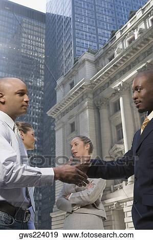 Side profile of two businessmen shaking hands with two businesswomen smiling View Large Photo Image Stock Photo - Side profile of two businessmen shaking hands with two businesswomen smiling. Fotosearch