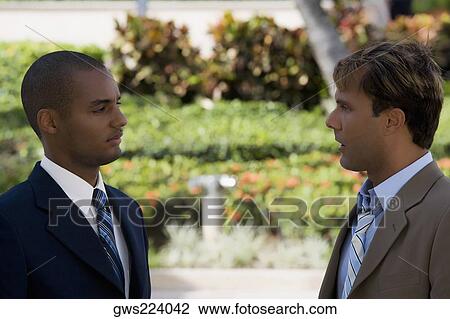 Side profile of two businessmen talking to each other View Large Photo Image Stock Image - Side profile of two businessmen talking to each other. Fotosearch