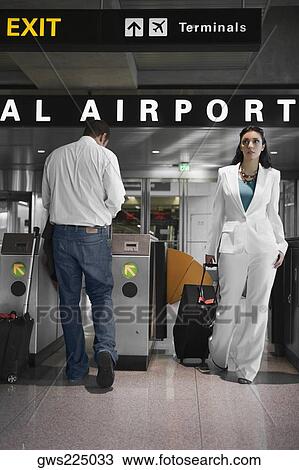 Businesswoman pulling her luggage and a mid adult man standing near a check-in machine at an airport View Large Photo Image Stock Image - Businesswoman pulling her luggage and a mid adult man standing near a check-in machine at an airport. Fotosearch