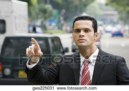 Stock Image - Close-up of a businessman hailing for a vehicle. Fotosearch