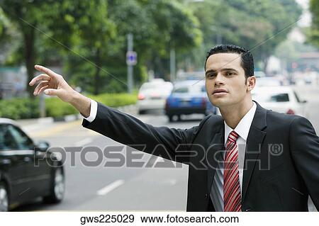 Stock Photo - Close-up of a businessman hailing for a vehicle. Fotosearch