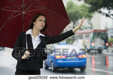 Stock Image - Close-up of a businesswoman hailing for a vehicle. Fotosearch