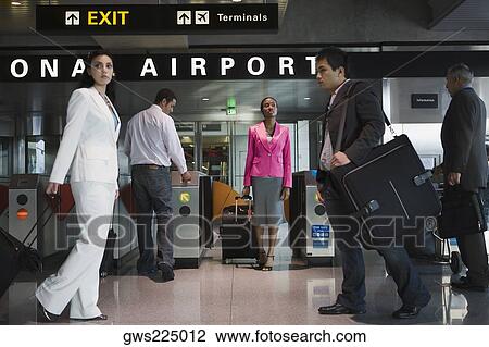 Stock Image - Five people walking at an airport. Fotosearch