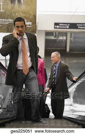 Four business executives standing on an escalator at an airport View Large Photo Image Stock Image - Four business executives standing on an escalator at an airport. Fotosearch