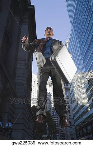 Low angle view of a businessman in mid-air View Large Photo Image Stock Photo - Low angle view of a businessman in mid-air. Fotosearch