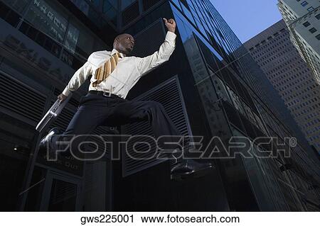 Low angle view of a businessman jumping with a briefcase View Large Photo Image Stock Image - Low angle view of a businessman jumping with a briefcase. Fotosearch