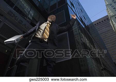 Stock Image - Low angle view of a businessman jumping with a briefcase. Fotosearch