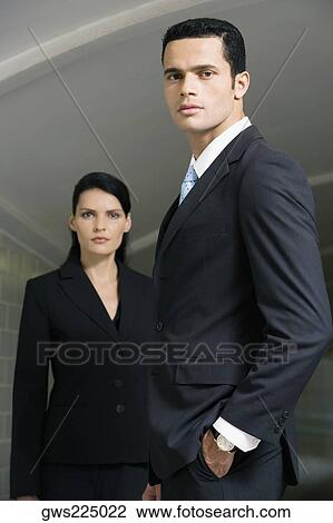 Portrait of a businessman standing with his hand in his pocket and a businesswoman standing behind him View Large Photo Image Stock Image - Portrait of a businessman standing with his hand in his pocket and a businesswoman standing behind him. Fotosearch