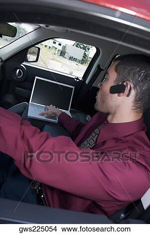 Picture - Side profile of a businessman using a laptop in a car. Fotosearch