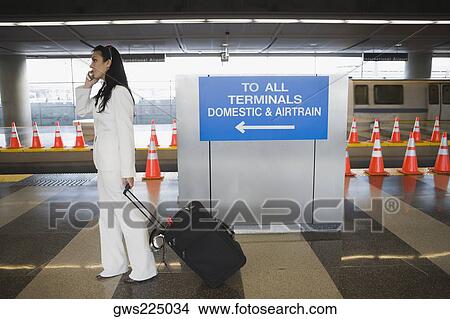 Side profile of a businesswoman talking on a mobile phone and pulling her luggage at a subway station View Large Photo Image Picture - Side profile of a businesswoman talking on a mobile phone and pulling her luggage at a subway station. Fotosearch